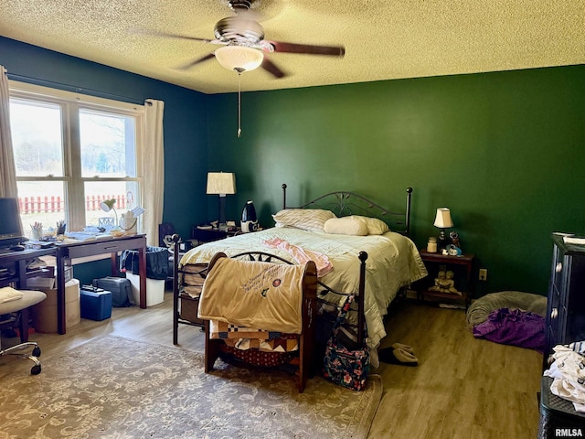 bedroom featuring a ceiling fan, a textured ceiling, and wood finished floors