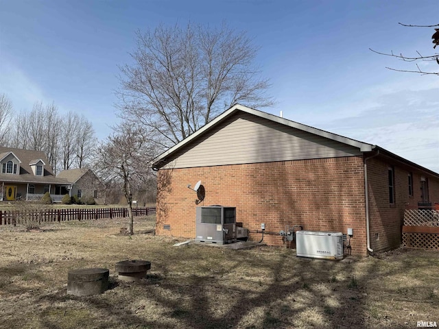 back of house featuring crawl space, fence, cooling unit, and brick siding