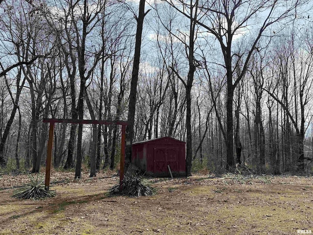 view of yard with an outbuilding, a storage unit, and a view of trees