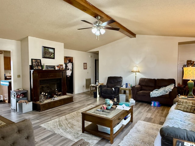 living area with visible vents, a fireplace with raised hearth, lofted ceiling with beams, a textured ceiling, and light wood-type flooring