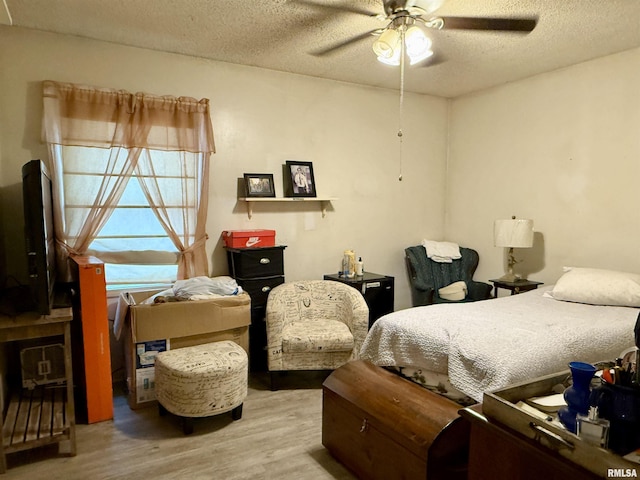 bedroom with a textured ceiling, ceiling fan, and wood finished floors