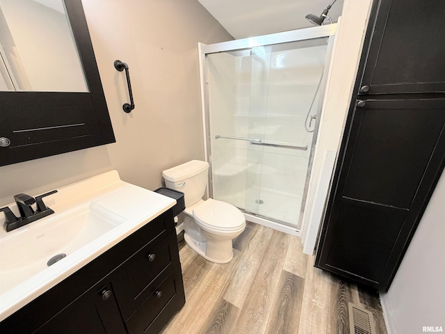 bathroom featuring toilet, a shower stall, wood finished floors, and vanity