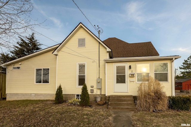 rear view of property with entry steps and a shingled roof