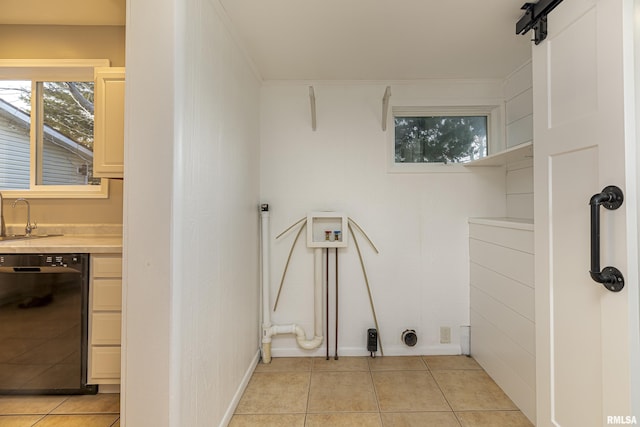 washroom featuring light tile patterned floors, laundry area, a barn door, and a sink