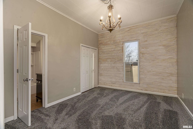 interior space with ornamental molding, a notable chandelier, carpet floors, wood walls, and a closet