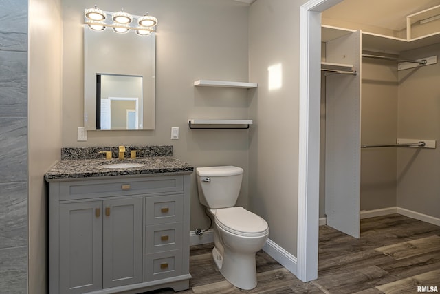 bathroom with vanity, wood finished floors, toilet, and baseboards