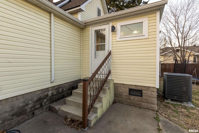 view of exterior entry featuring cooling unit, crawl space, and fence