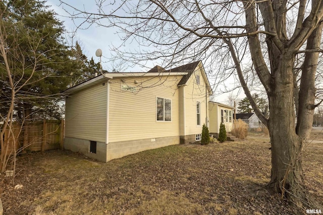 view of side of home featuring crawl space and fence