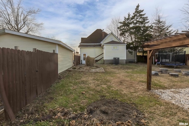 exterior space with entry steps, central air condition unit, fence, a yard, and a trampoline