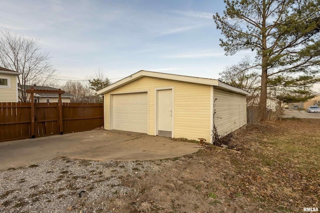 detached garage featuring driveway and fence