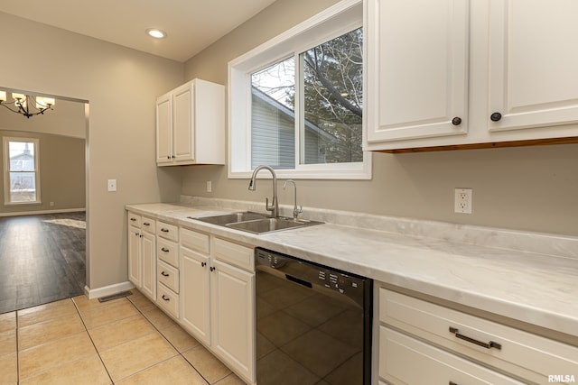 kitchen featuring black dishwasher, light tile patterned floors, a sink, and white cabinetry