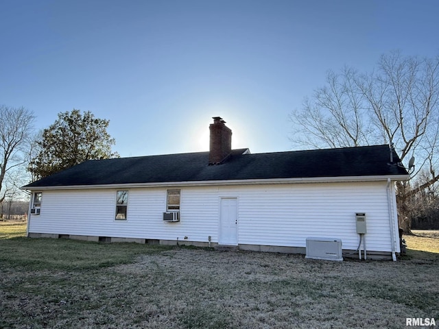 back of property featuring a chimney, cooling unit, and a yard