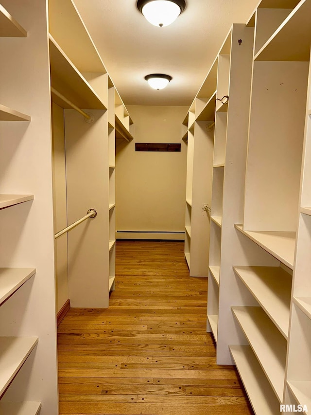 spacious closet featuring a baseboard radiator and wood finished floors