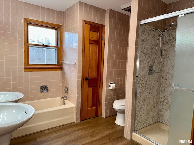 full bath featuring toilet, wood finished floors, tile walls, and a shower stall