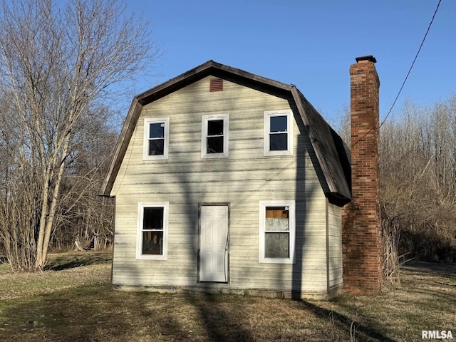 back of property featuring a chimney and a gambrel roof