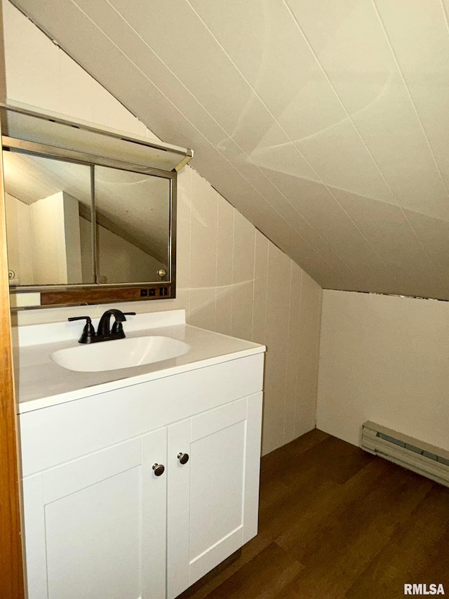 bathroom with a baseboard radiator, vaulted ceiling, wood finished floors, and vanity