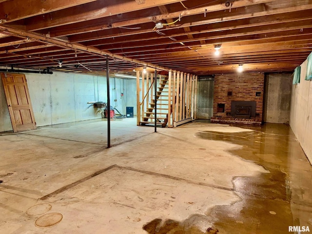 unfinished basement featuring a wood stove and stairway