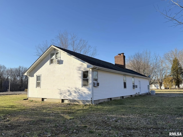 view of side of property with a chimney, central AC, and a yard