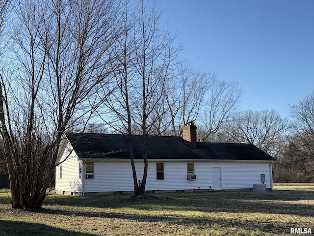 view of side of property featuring a chimney, central AC unit, cooling unit, and a yard