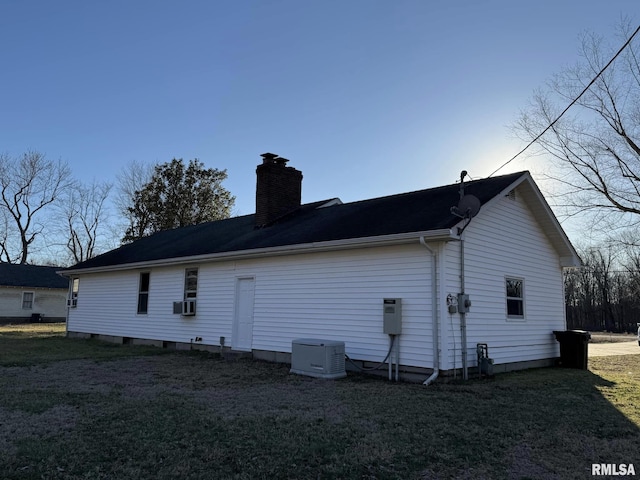 back of house with a chimney and a yard