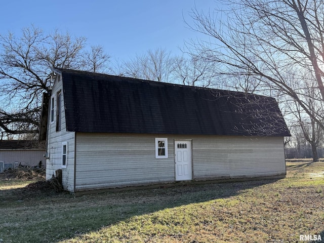 exterior space featuring a yard, a shingled roof, and a gambrel roof