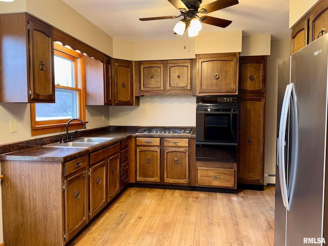 kitchen featuring a warming drawer, stainless steel appliances, dark countertops, a baseboard heating unit, and a sink