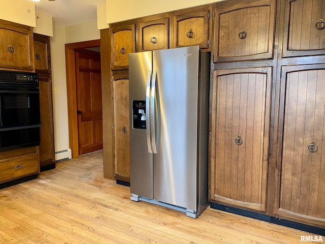 kitchen featuring light wood finished floors, baseboard heating, brown cabinets, and stainless steel fridge with ice dispenser