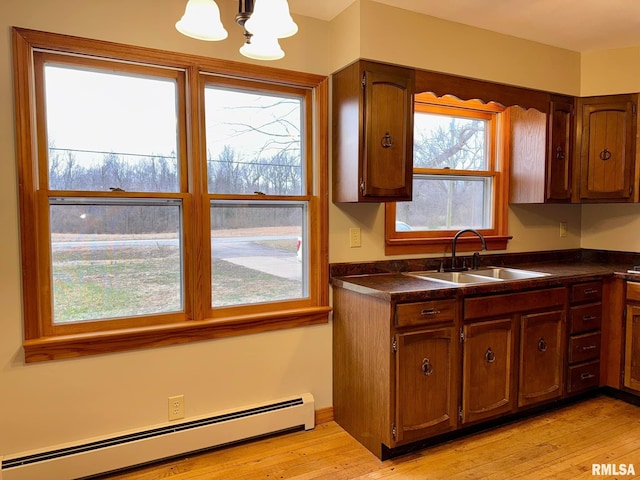 kitchen featuring dark countertops, light wood-style floors, a baseboard heating unit, and a sink