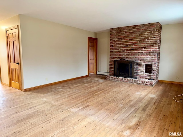 unfurnished living room featuring a brick fireplace, baseboards, wood-type flooring, and baseboard heating