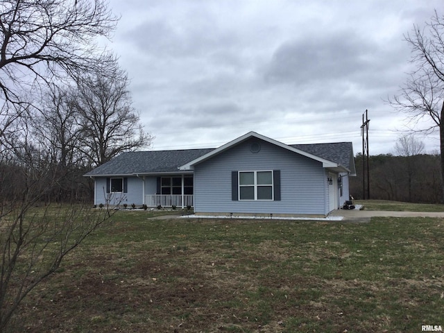 view of front of house featuring covered porch, roof with shingles, and a front yard