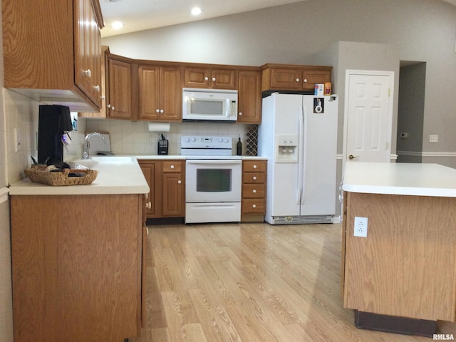 kitchen featuring white appliances, light wood finished floors, light countertops, vaulted ceiling, and a sink