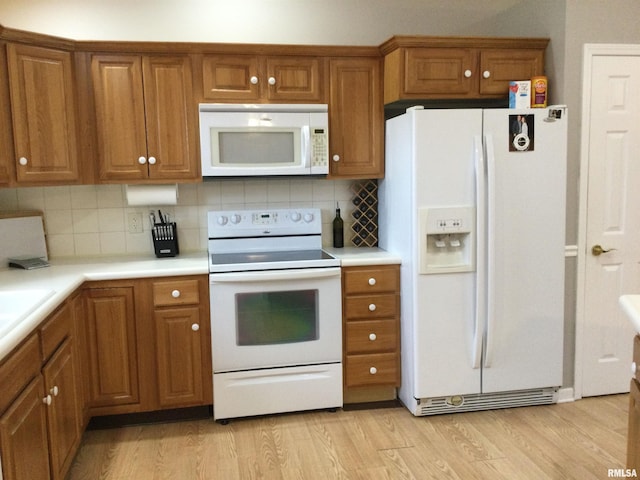 kitchen with white appliances, light wood-style flooring, brown cabinets, and light countertops