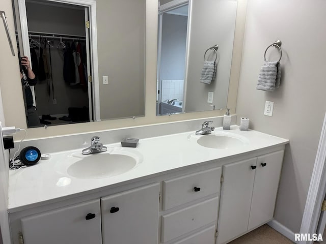 full bath featuring double vanity, a sink, and a walk in closet