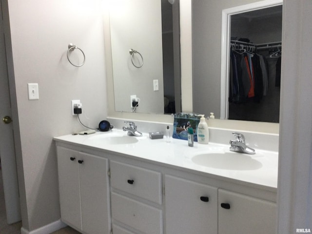 full bathroom featuring double vanity, a sink, and a walk in closet