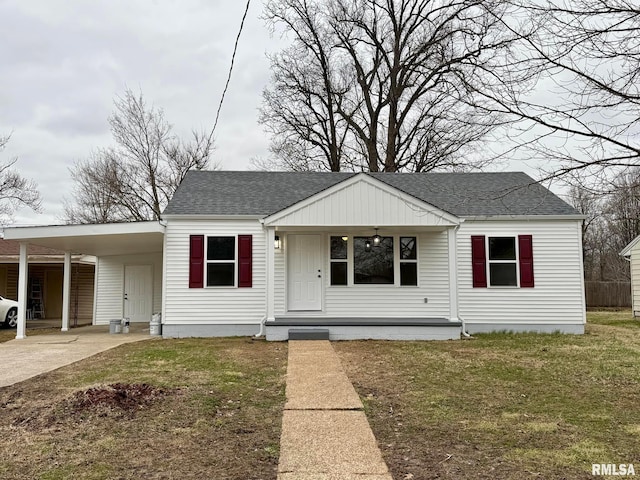 view of front facade with driveway, an attached carport, a front yard, and a shingled roof