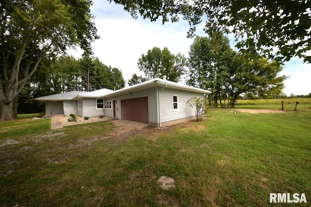 rear view of property with driveway, an attached garage, and a yard