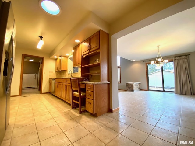 kitchen with light tile patterned floors, a sink, baseboards, appliances with stainless steel finishes, and baseboard heating