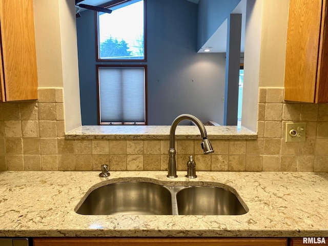 room details with light stone counters, decorative backsplash, and a sink