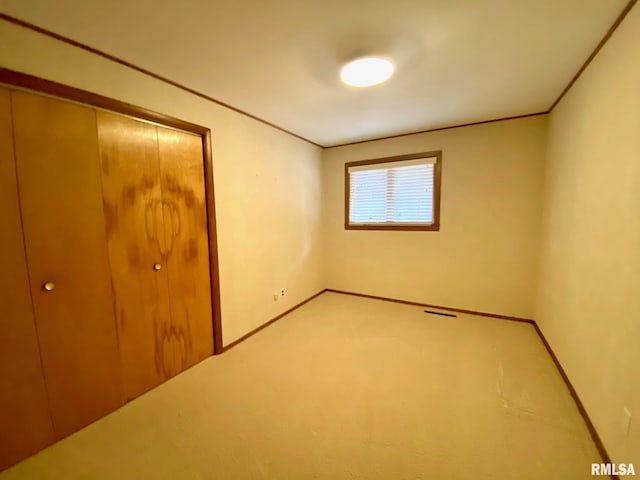 unfurnished bedroom with baseboards, ornamental molding, a closet, and light colored carpet