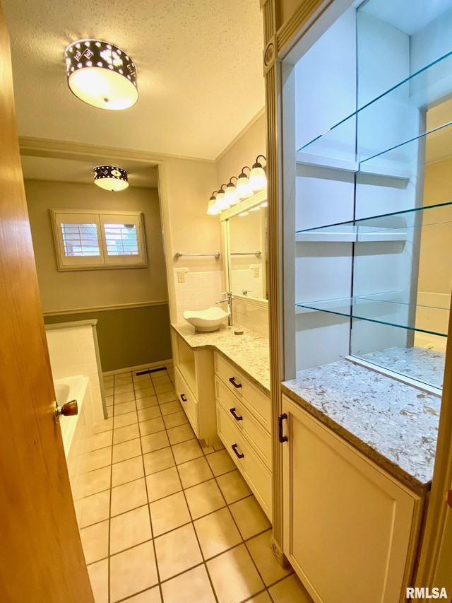 full bathroom with tiled bath, tile patterned flooring, vanity, and a textured ceiling