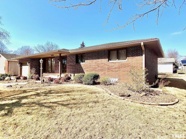 ranch-style home featuring a garage, brick siding, and a front yard