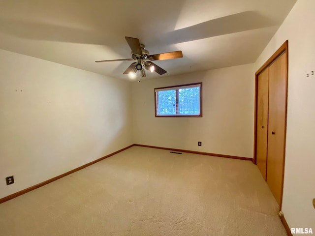 unfurnished bedroom featuring ceiling fan, light colored carpet, visible vents, baseboards, and a closet