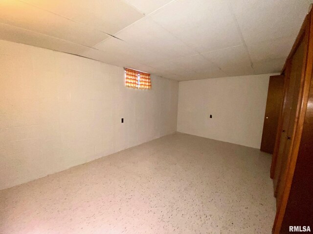 finished basement featuring concrete block wall and a drop ceiling