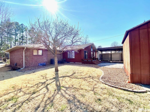 back of property with a yard, an attached carport, and brick siding