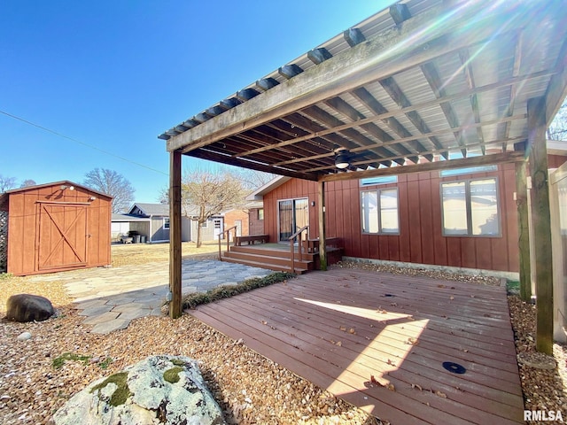 deck with a storage shed, a patio area, an outbuilding, and a ceiling fan