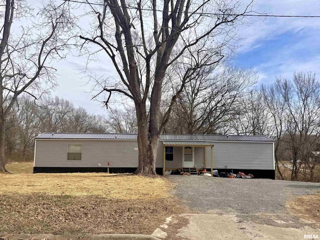 manufactured / mobile home featuring entry steps, gravel driveway, and metal roof