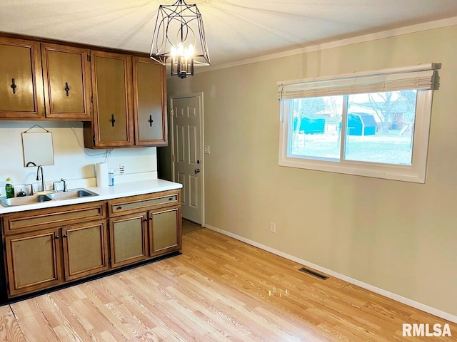 kitchen with light countertops, brown cabinetry, a sink, and light wood-style floors