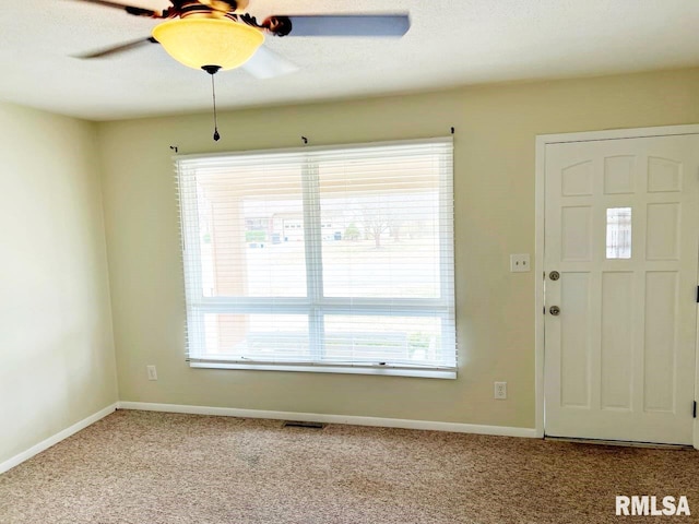 foyer entrance with a ceiling fan, carpet, visible vents, and baseboards