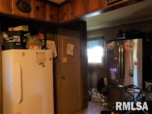 kitchen featuring brown cabinetry, stainless steel fridge, and freestanding refrigerator