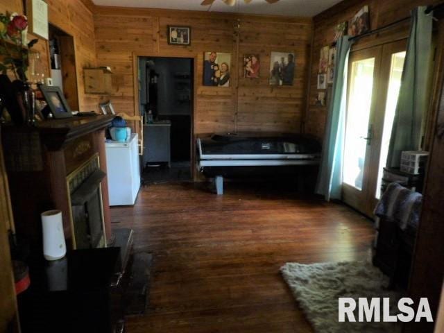 interior space with dark wood-style flooring, wood walls, and ceiling fan